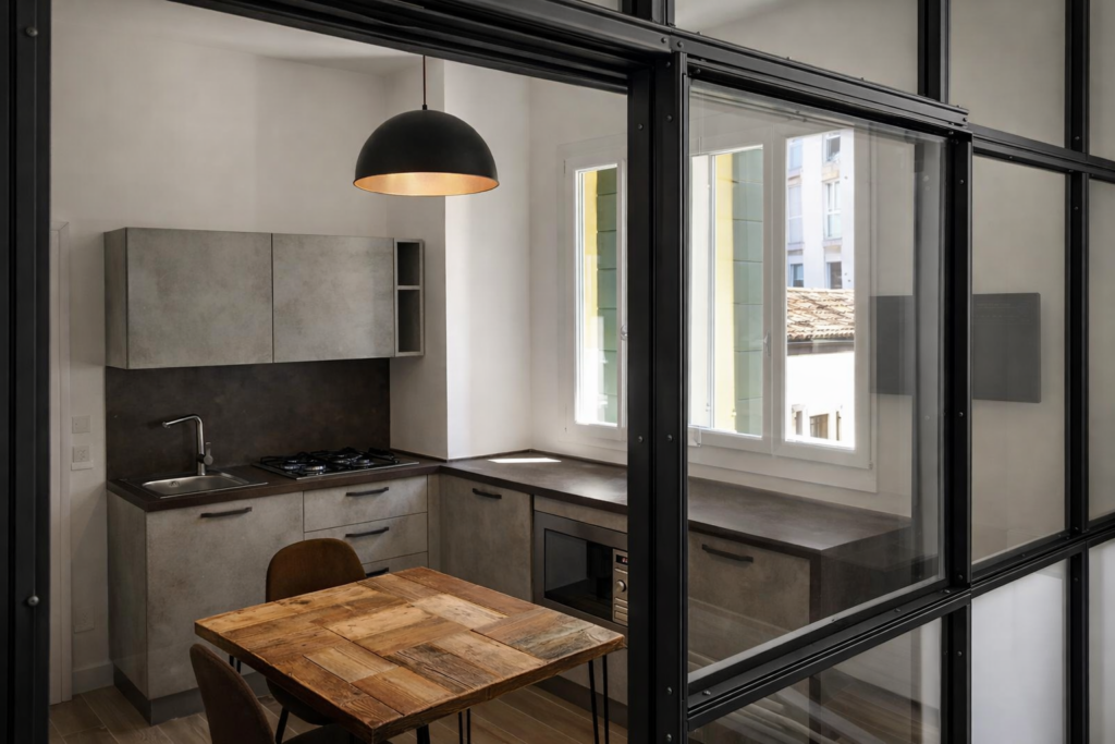 Ristrutturazione di mini appartamento nel centro storico di Padova: cucina compatta separata da vetrata in ferro e vetro su misura